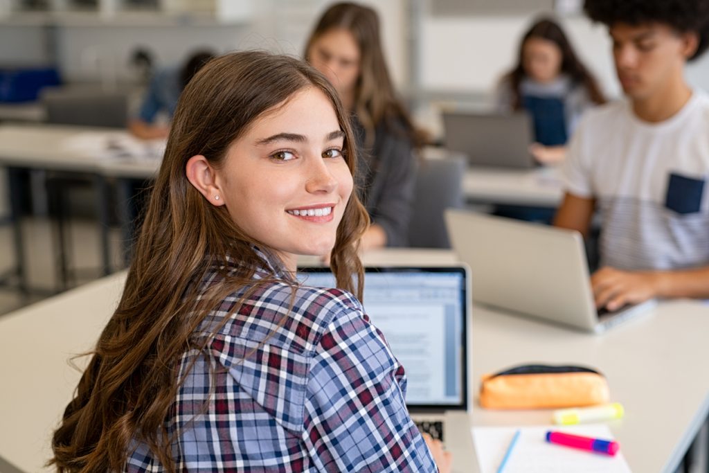 Happy smiling college girl studying on laptop